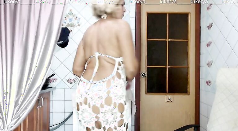 Excited Lukerya tries on long dresses in the kitchen.