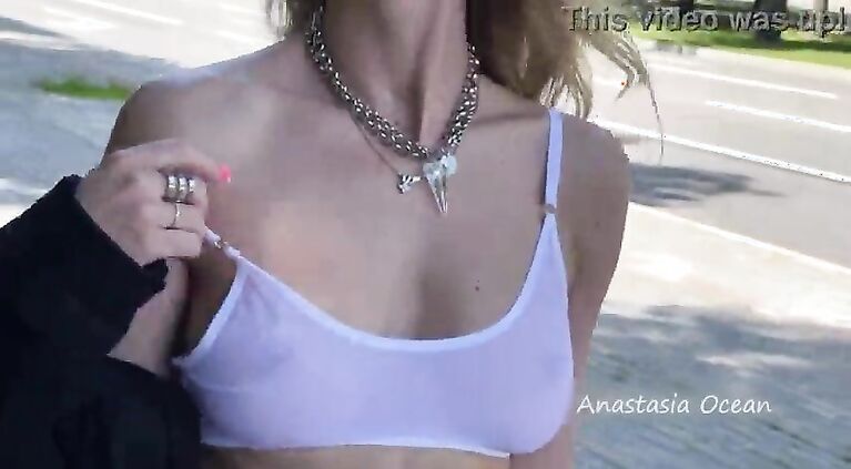 Shows breasts in the city, in a crowded place. public